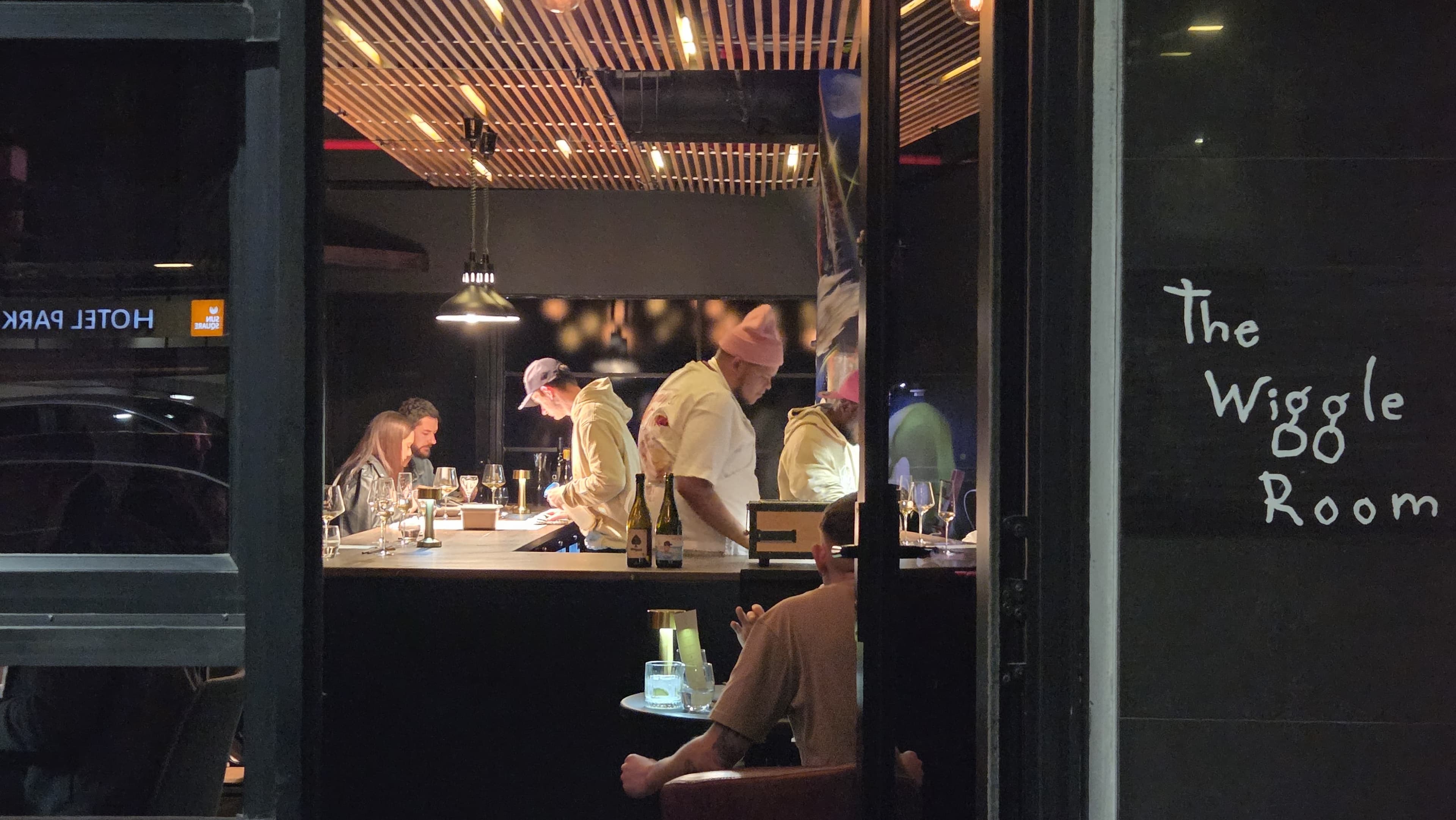 Night exterior of The Wiggle Room on Bree Street — illuminated venue signage and warm bar light through the windows